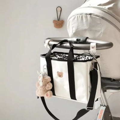 Sac à langer crème et noir attaché à une poussette